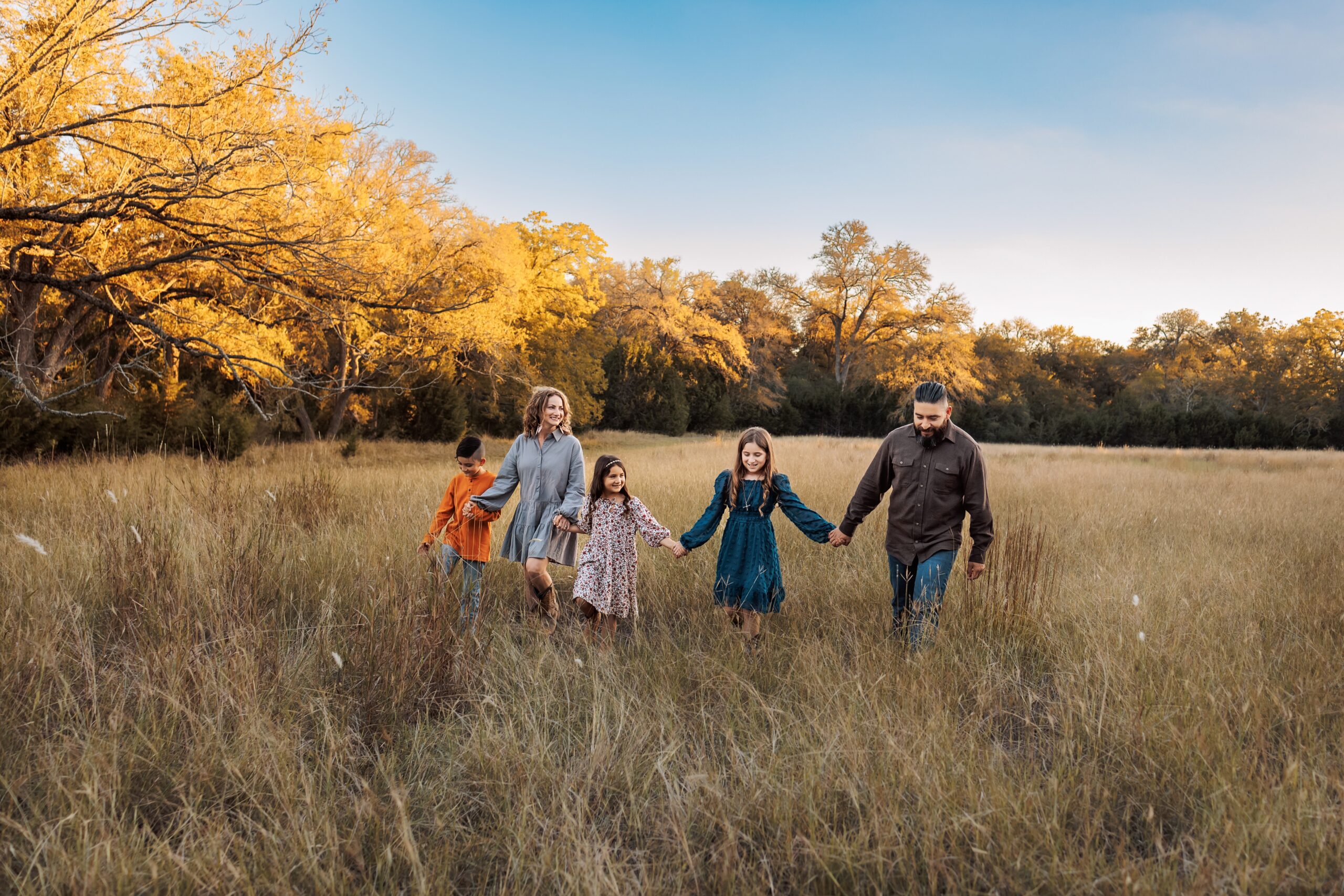 family holding hands and walking in field family photography boerne tx